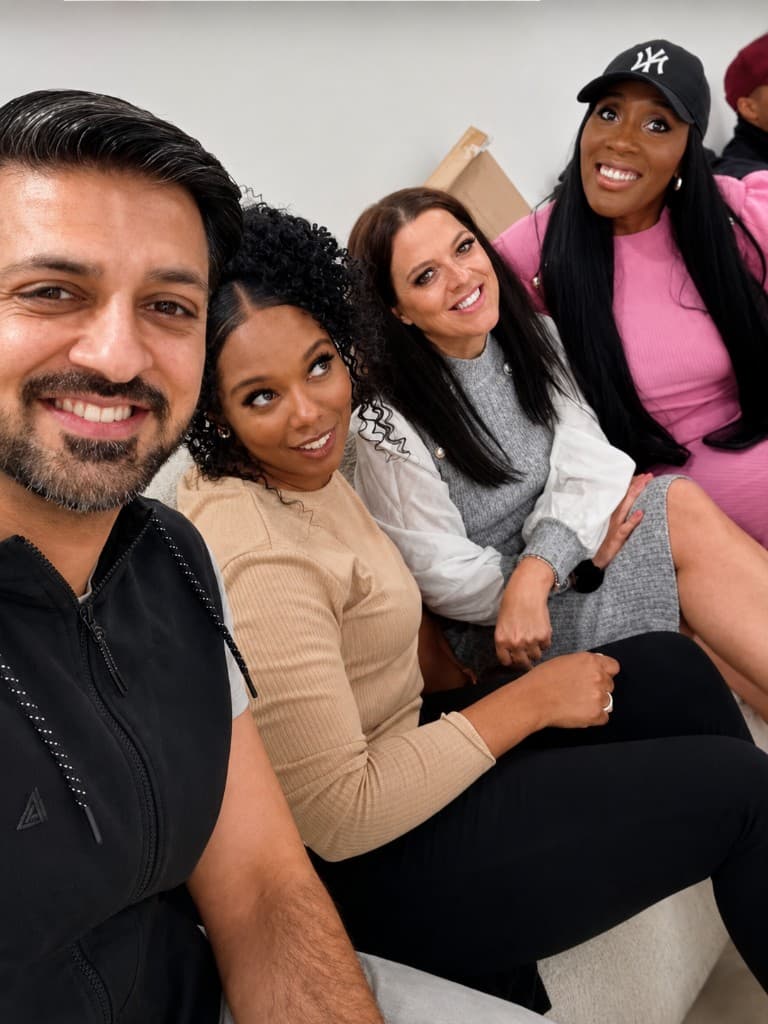 Group selfie of four Teacher's Surgery team members smiling together on a sofa